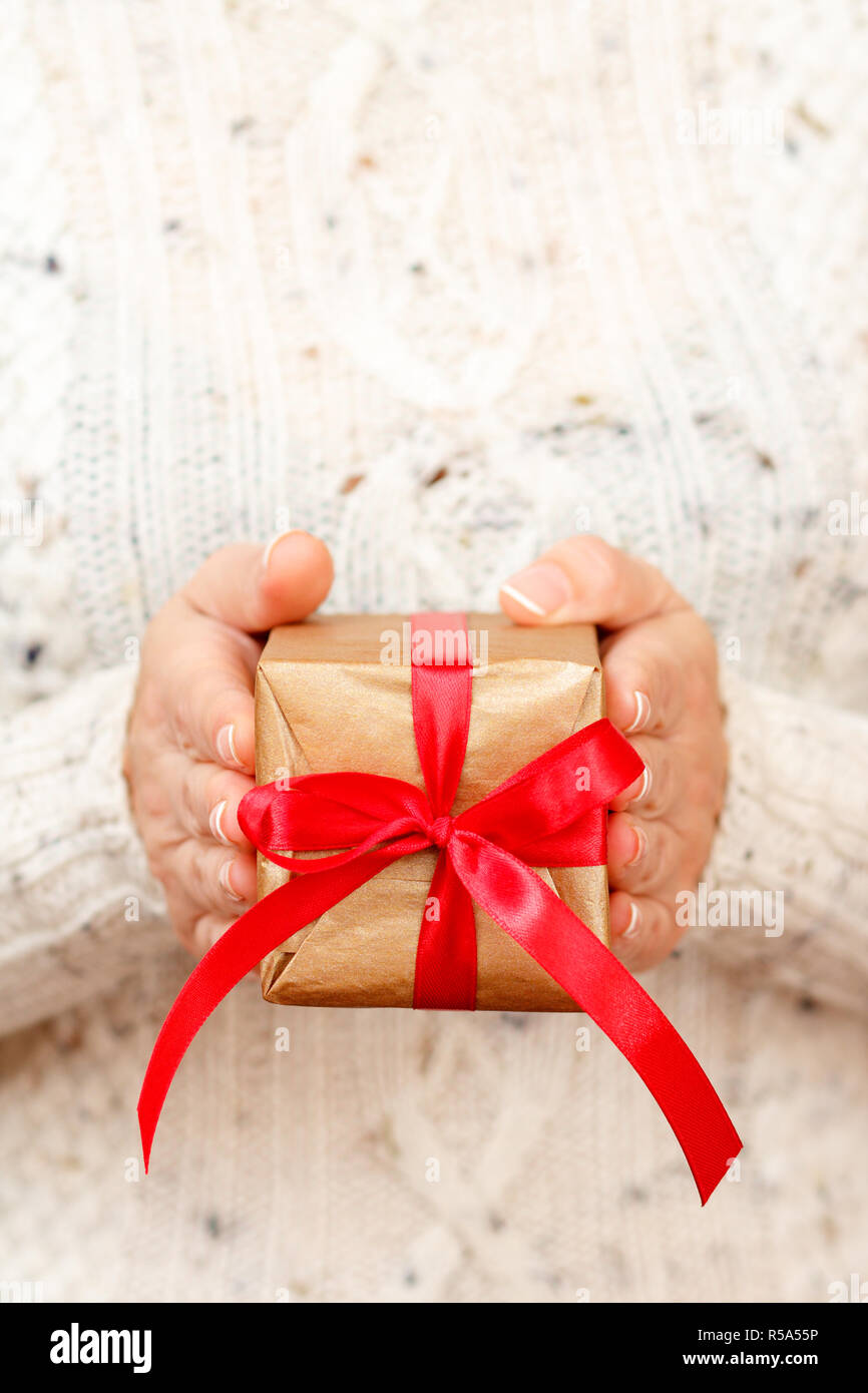 Female hand hold a box wrapped in red paper and tied with a red silk ribbon,  holiday Stock Photo by ndanko