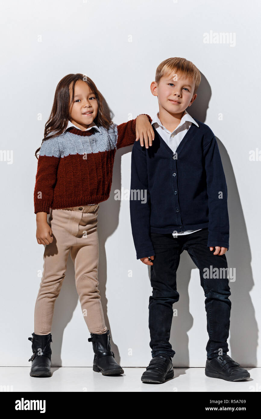 The portrait of cute little kids boy and girl in stylish jeans clothes  looking at camera against white studio wall. Kids fashion and happy  emotions concept Stock Photo - Alamy