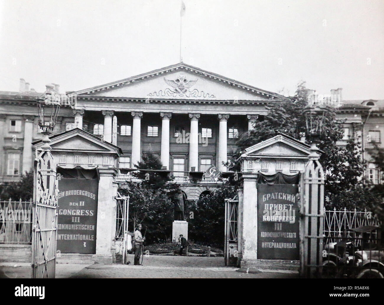 'Former court of the page-boys'. During the imperial period, Smolny Institute was an educational establishment for noble girls, where they used to learn good manners at the tsarist court. After 1917, the building was used as the headquarters for the Bolshevik Party, before the Party moved to Moscow the following year.   The two banners at the entrance read: 'Fraternal greetings to the IInd Congress of the IIIrd Communist International'. Stock Photo