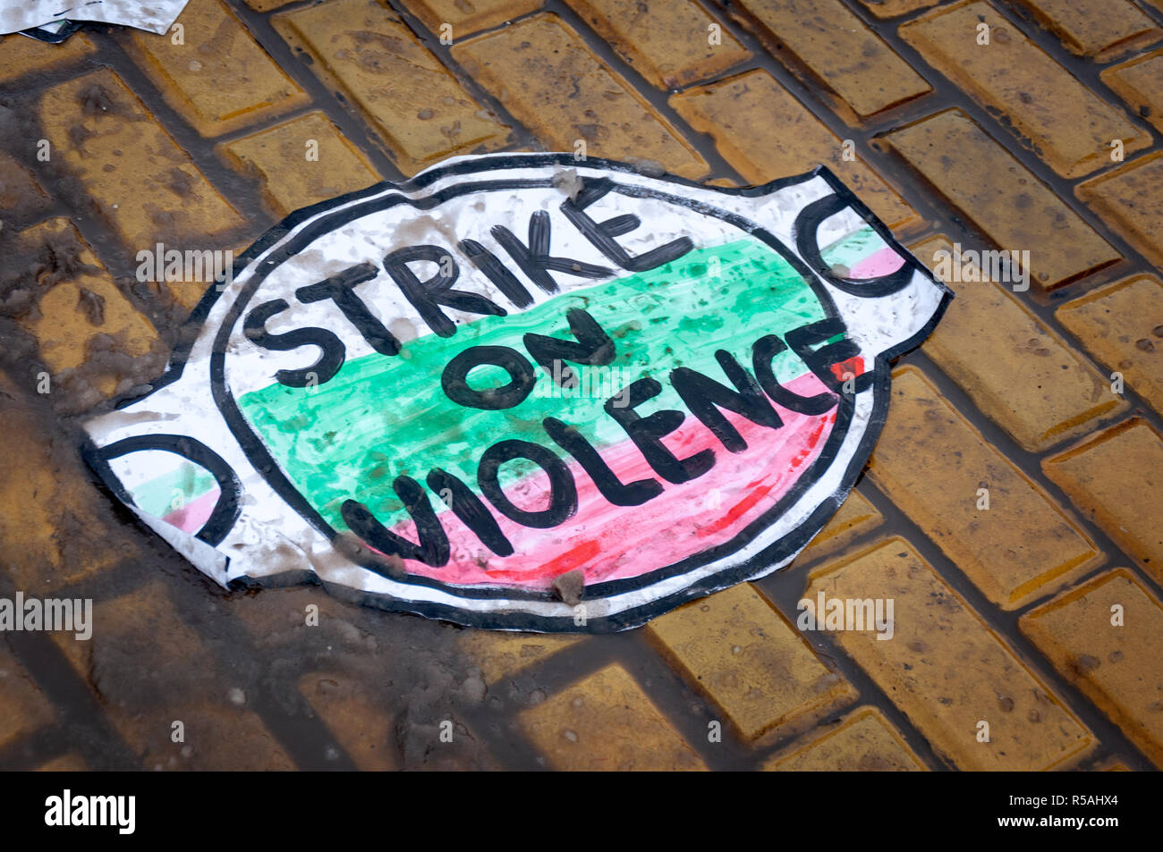 Placard against violence on the ground during one of the FEMEN activists protest. Bulgaria flag colors on placard. Stock Photo