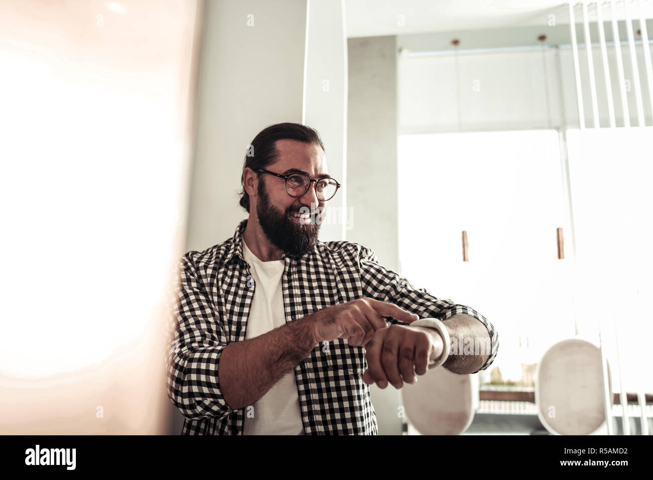New device. Delighted nice man using his modern watch while setting the time Stock Photo