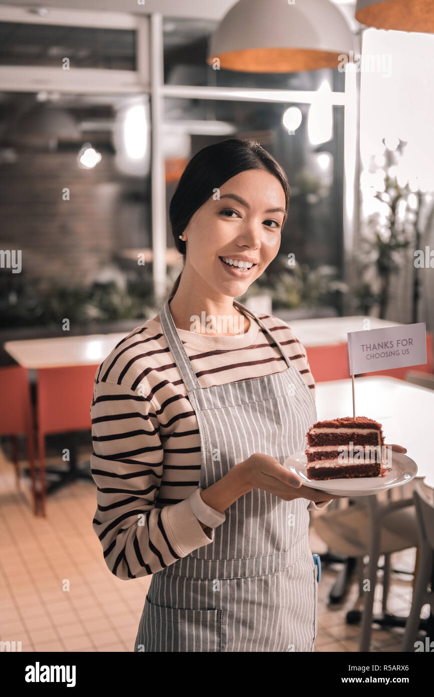 Appealing female entrepreneur holding tasty cake from her cafe Stock Photo