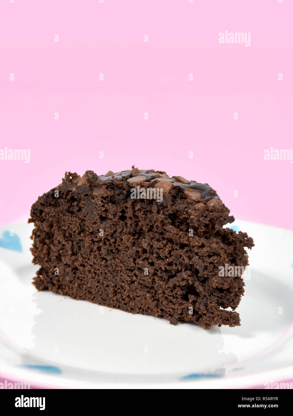 Moist chocolate cake on pretty plate made without eggs and with vegetable oil instead of butter. Against a pink background. Stock Photo