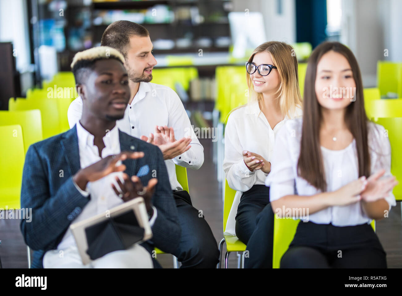 Multi ethnic business group greets somebody with clapping and smiling Stock Photo