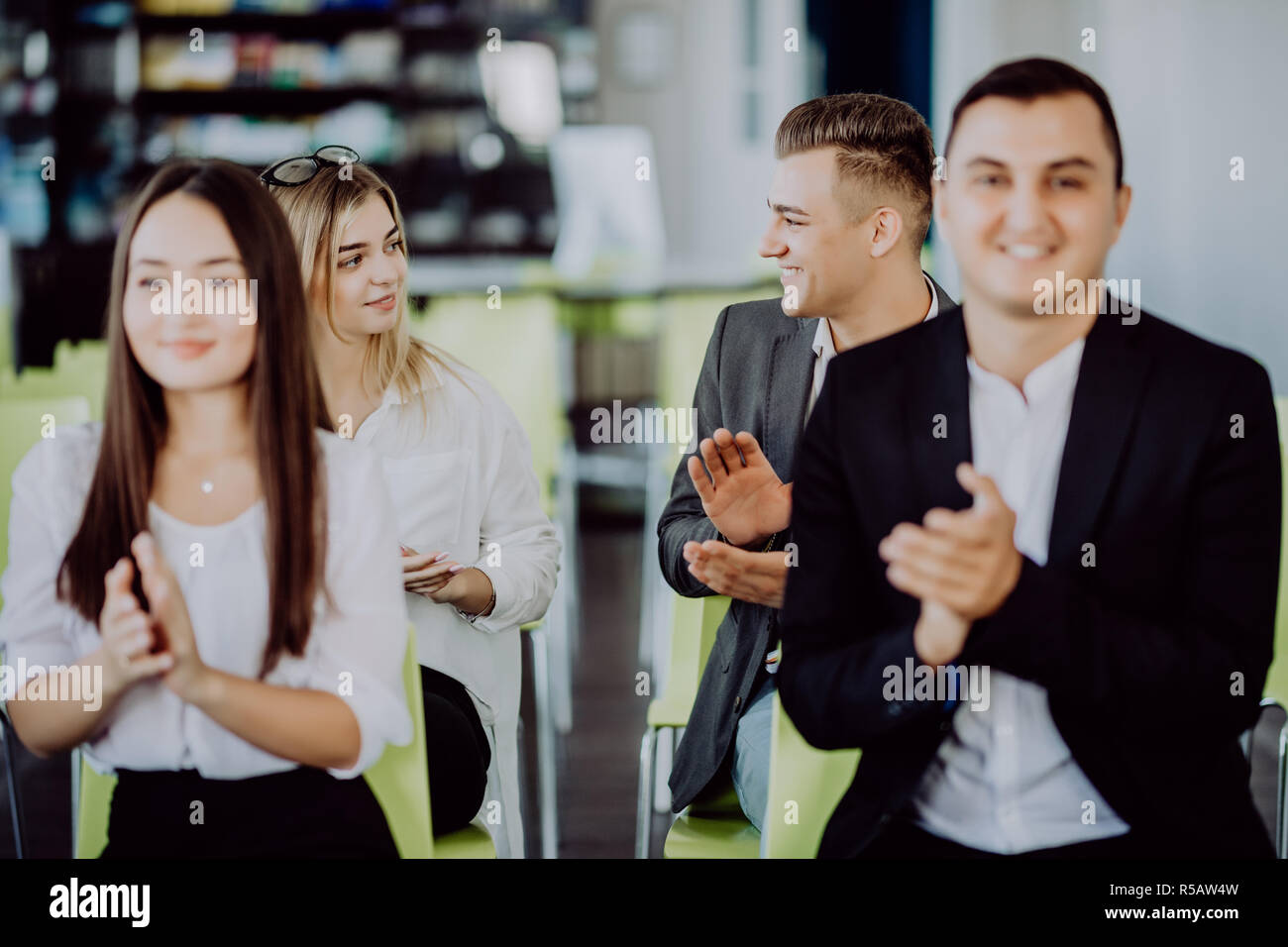 Multi ethnic business group greets somebody with clapping and smiling Stock Photo
