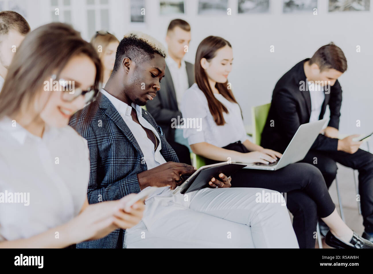 Diverse office people working on mobile phones, corporate employees holding smartphones at meeting, serious multiracial businessmen and businesswomen  Stock Photo