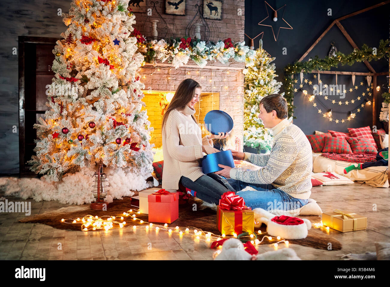 Husband and wife give presents at home on Christmas Day.  Stock Photo