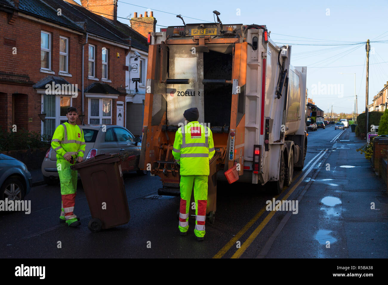 Men wearing biffa jackets collecting household rubbish bins and emptying into dustcart, rubbish collection by council workers Stock Photo