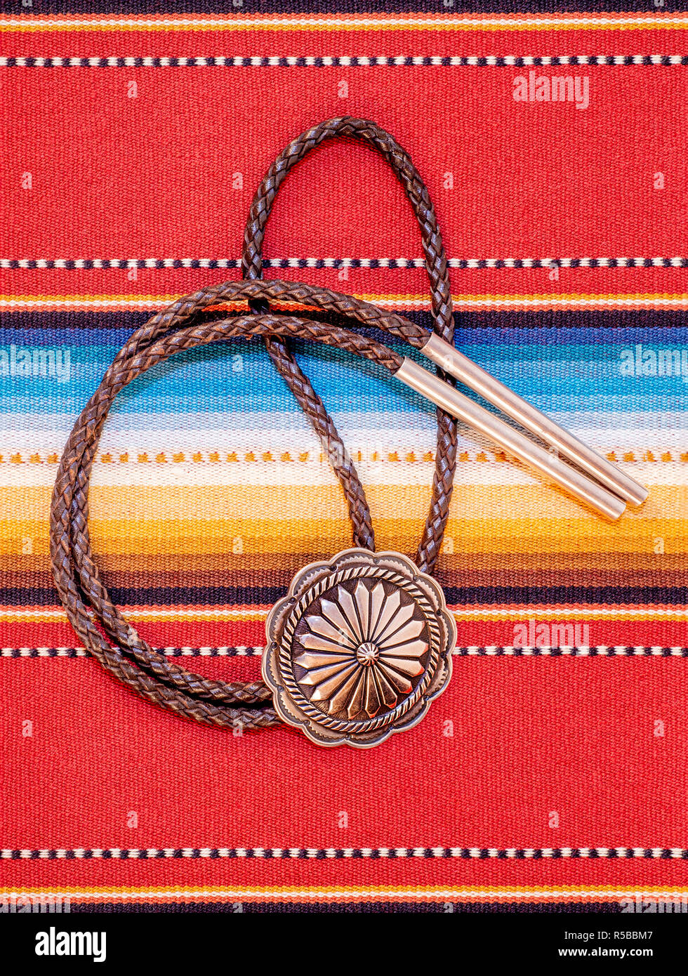 Vintage Sterling Silver Bolo Tie with Concho and Silver Tips on colorful southwestern hand woven fabric. Stock Photo