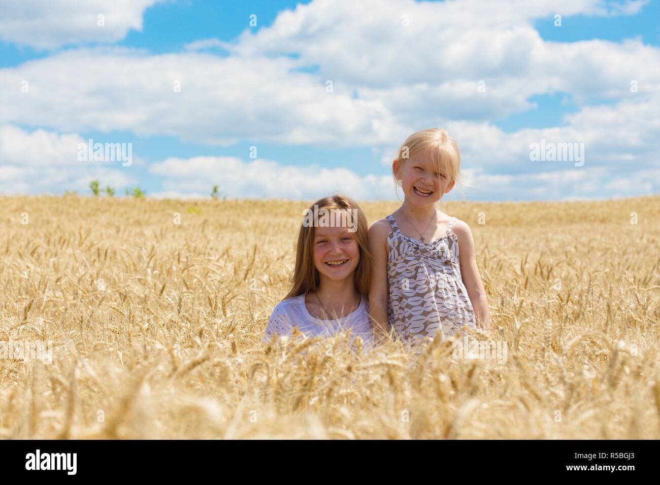 two smiling sisters sitting at the wheat field Stock Photo - Alamy