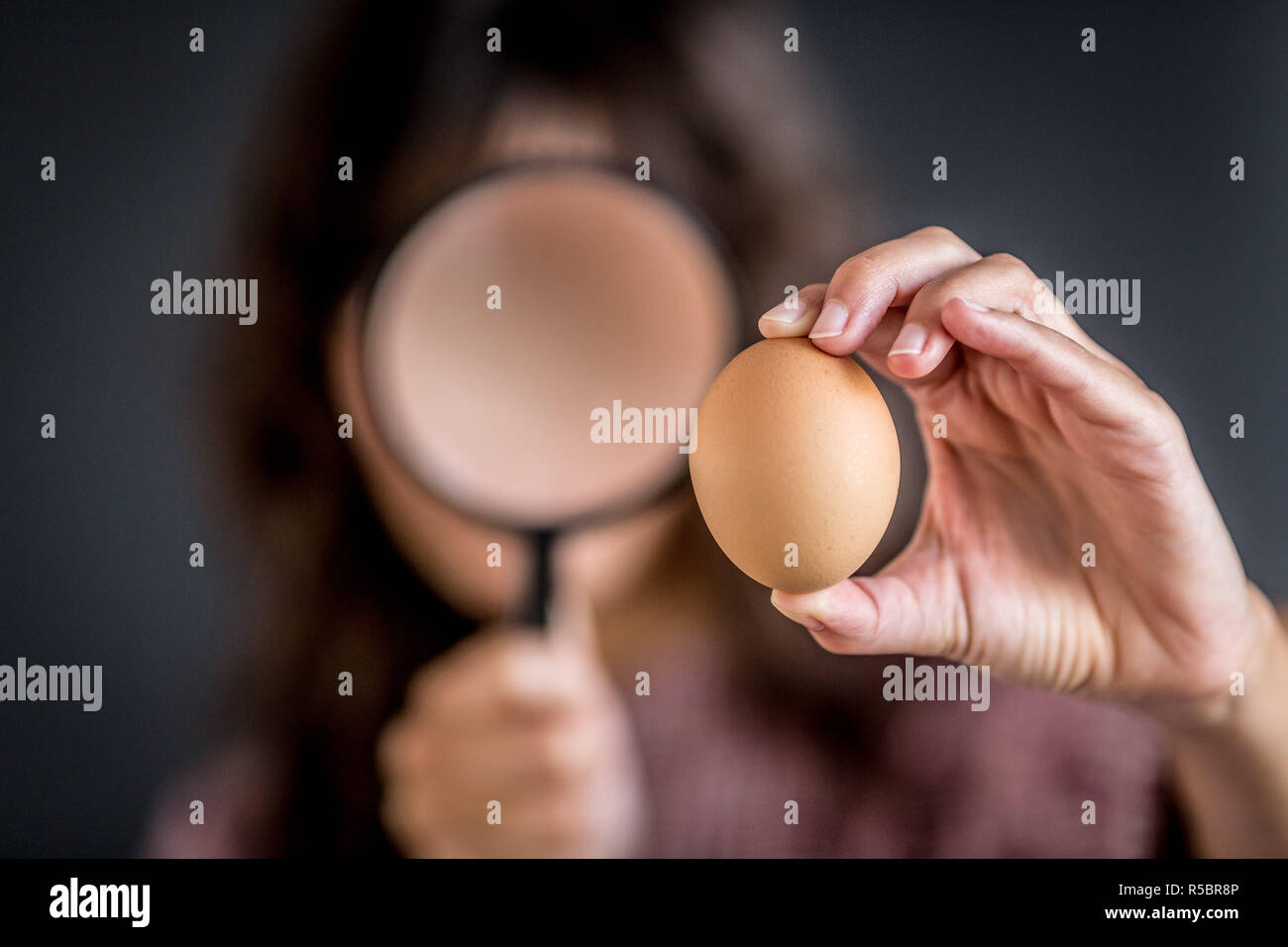Woman watching an egg with a magnifying glass. Stock Photo