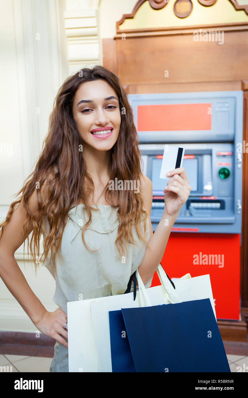 Brunette young lady using an automated teller machine . Woman withdrawing money or checking account balance Stock Photo