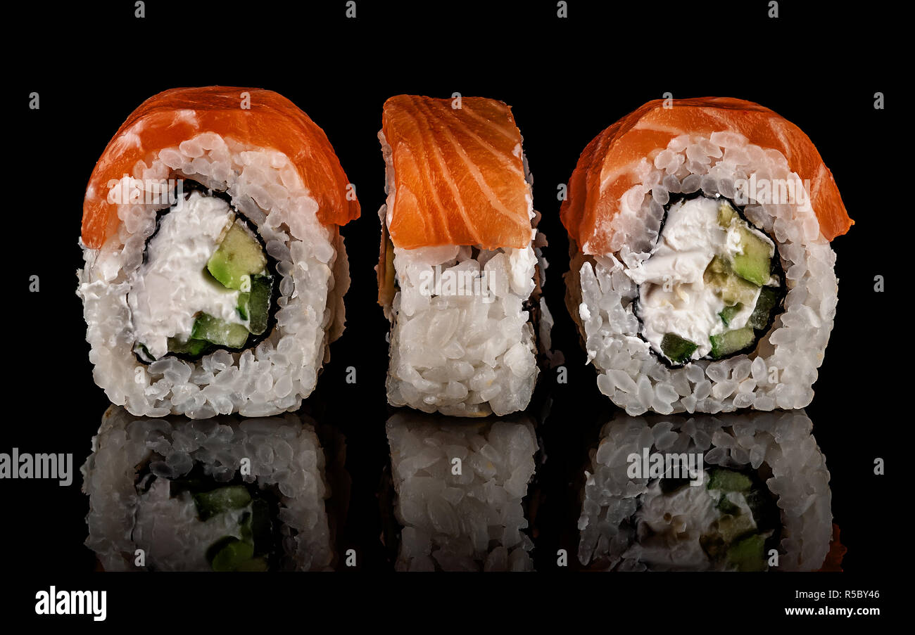 Three pieces of sushi rolls Philadelphia. Black background. Reflection. Stock Photo