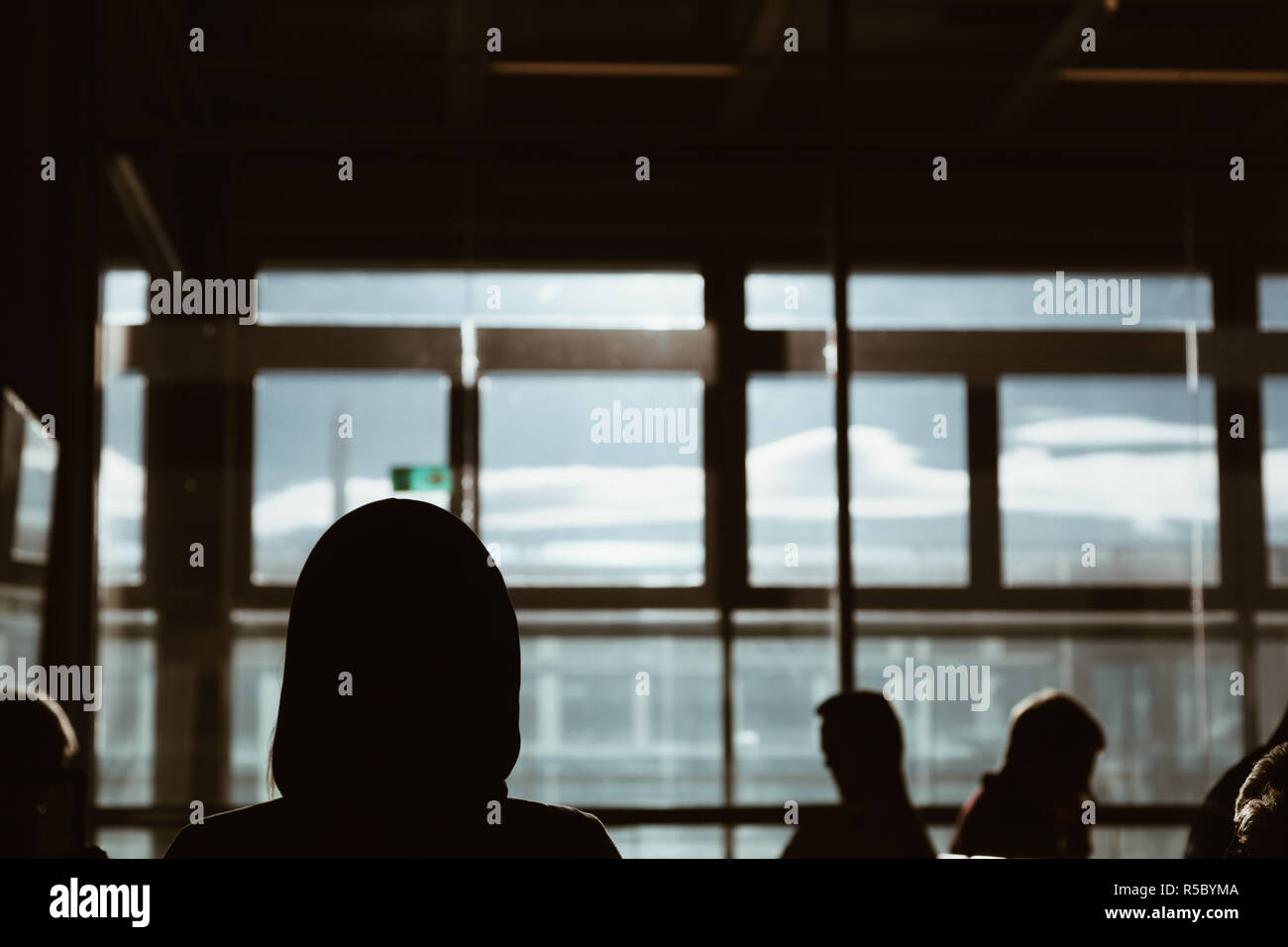 back view silhouette of girl wearing Sweatshirts waiting in the airport with other passenger