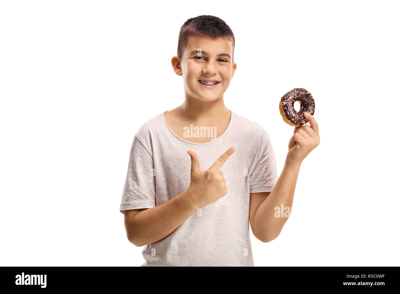 Smiling boy holding a chocolate donut and pointing isolated on white background Stock Photo