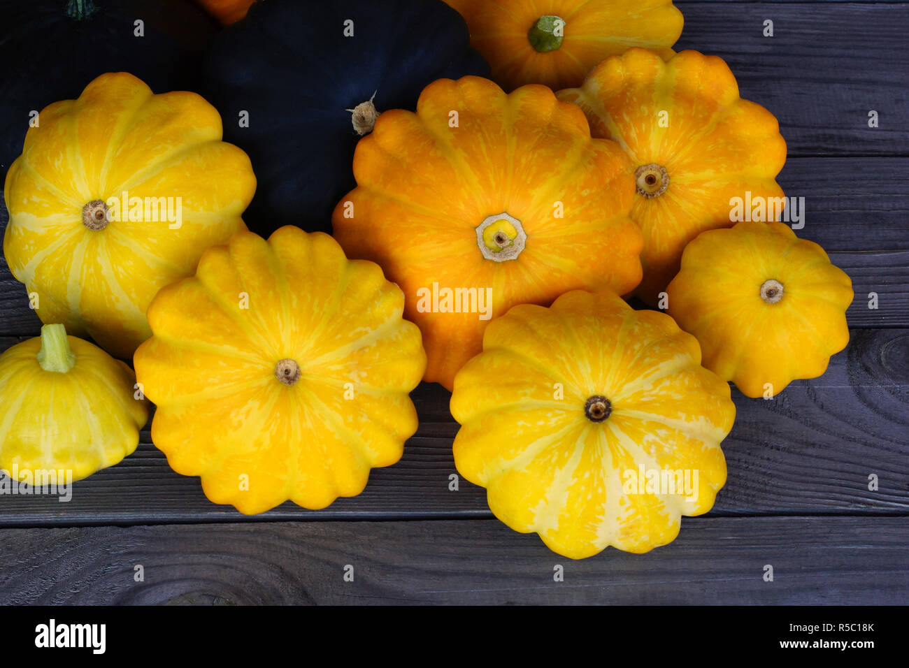 Yellow and green patissons on a rustic wooden table. Stock Photo