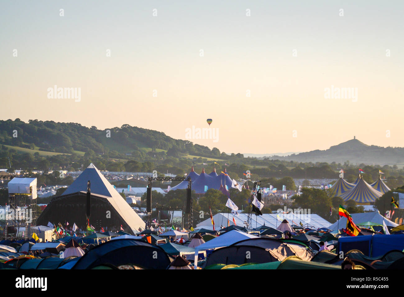 Hot air balloon rising in the distance above Glastonbury Festival Stock Photo