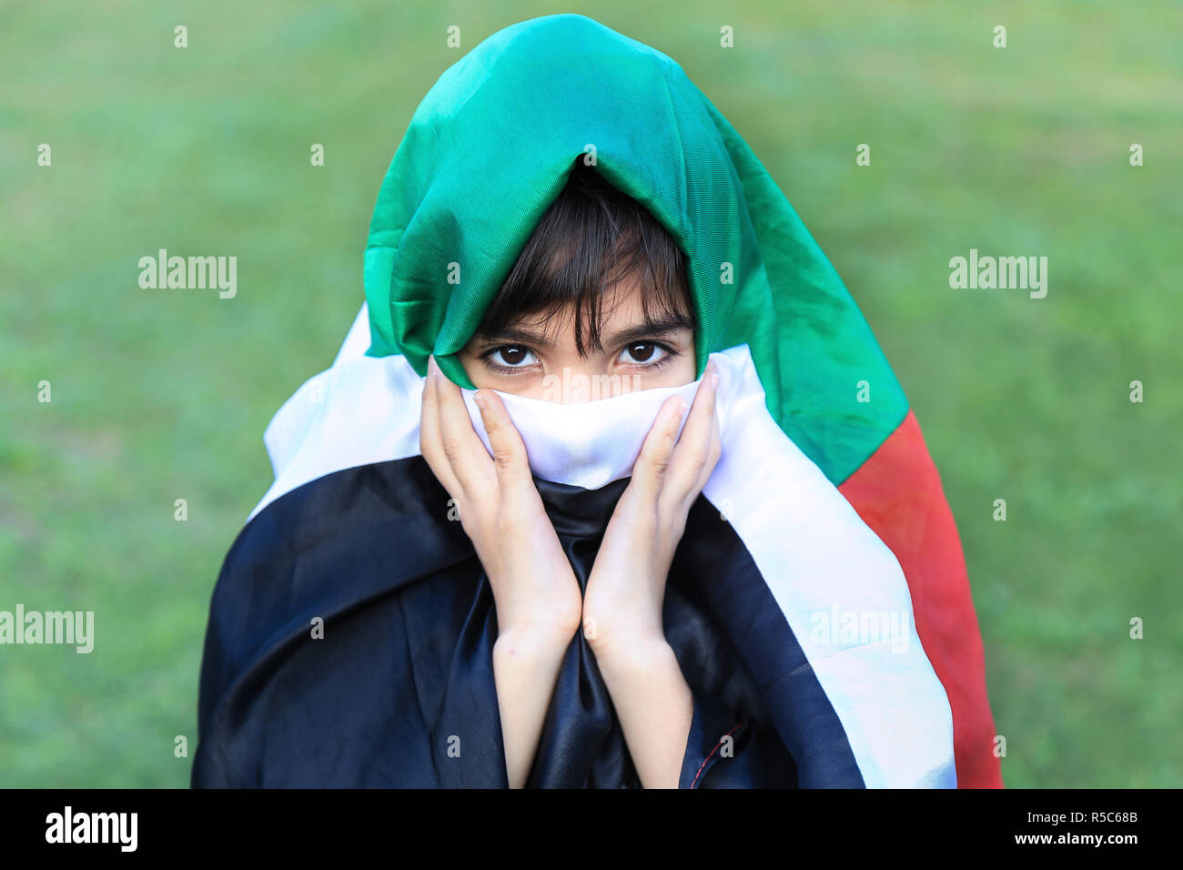 Palestinian little girl masked with Palestinian flag. Stock Photo