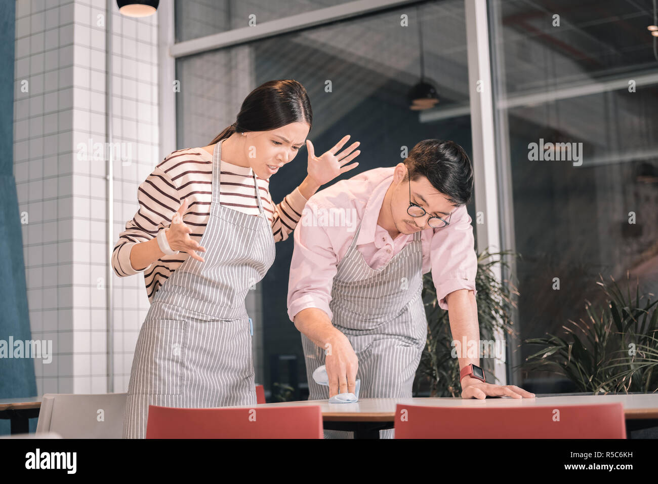 Owner of cafeteria feeling unsatisfied checking the cleanness of table Stock Photo