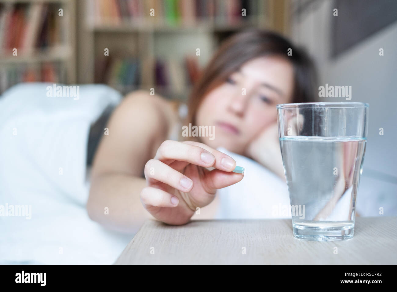 Woman feeling sick and taking medicine pill, focus on the medicine pill Stock Photo