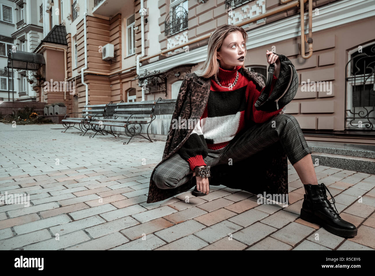Model posing. Blonde-haired professional photo model wearing nice clothes posing outside the street Stock Photo