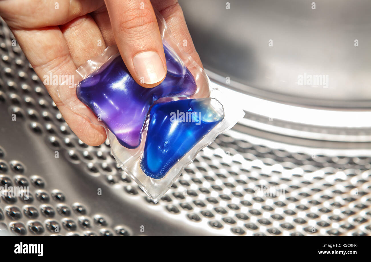 blue gel caps in hand for washing mashine, liquid coloured detergent