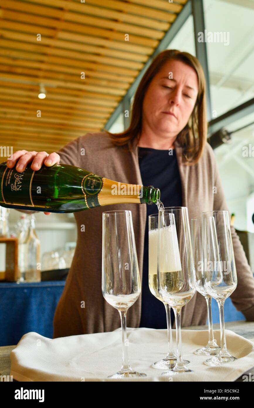 Woman pouring champagne sparkling wine from a bottle into glasses and