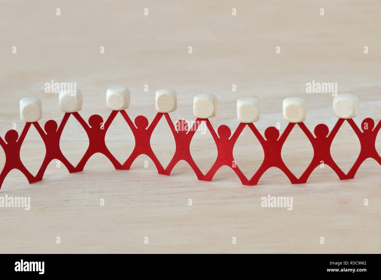 Paper people chain holding blank wooden cubes Stock Photo