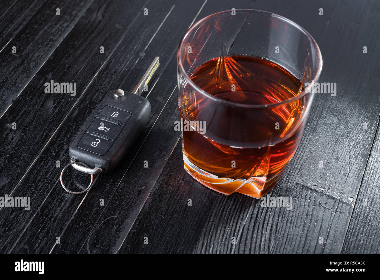 Car key and whiskey alcohol drink in a glass on black wooden table. Don ...