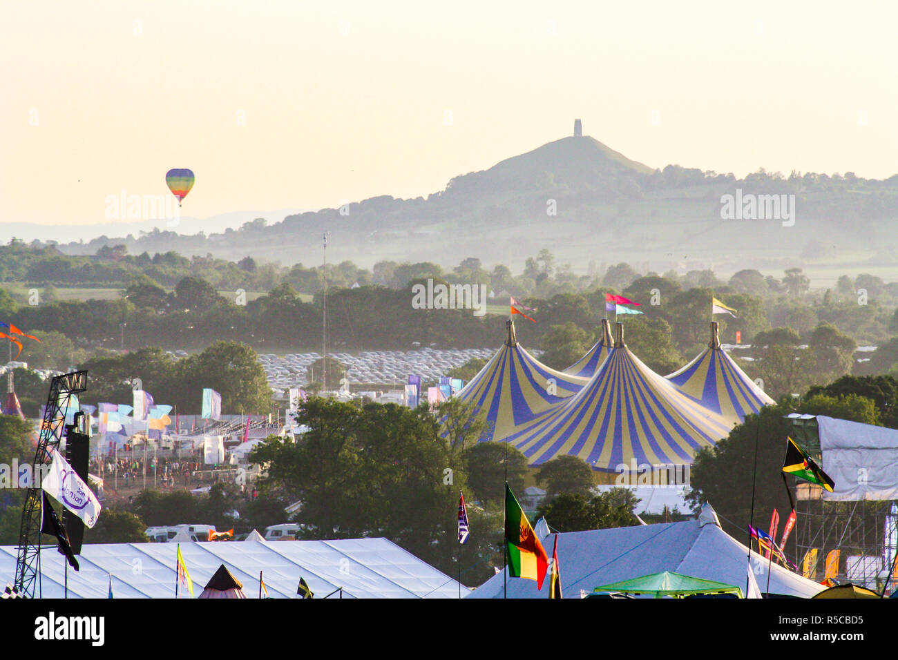 The pyramid stage at Glastonbury Festival with a hot air balloon rising in the distance Stock Photo