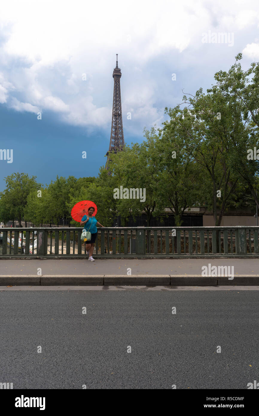 Young girl with red umbrella on vacation in paris looking at eiffel