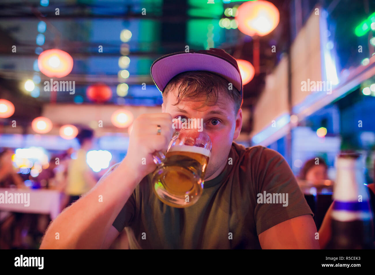 Man drinks beer. Side view of handsome young guy drinking lager pint