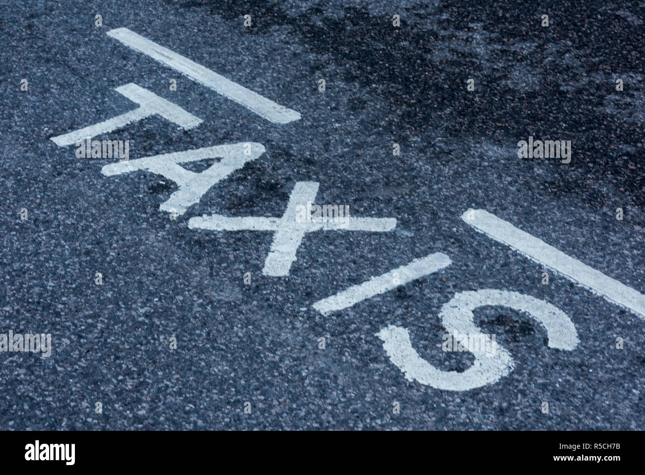 taxi sign on a taxi rank painted in white letters on the tarmac road. Stock Photo