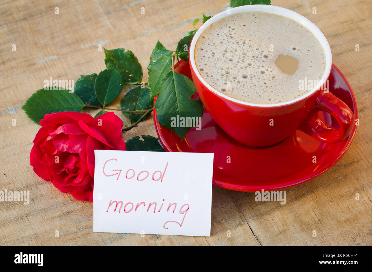 Coffee cup with red rose flower and notes good morning on wooden ...