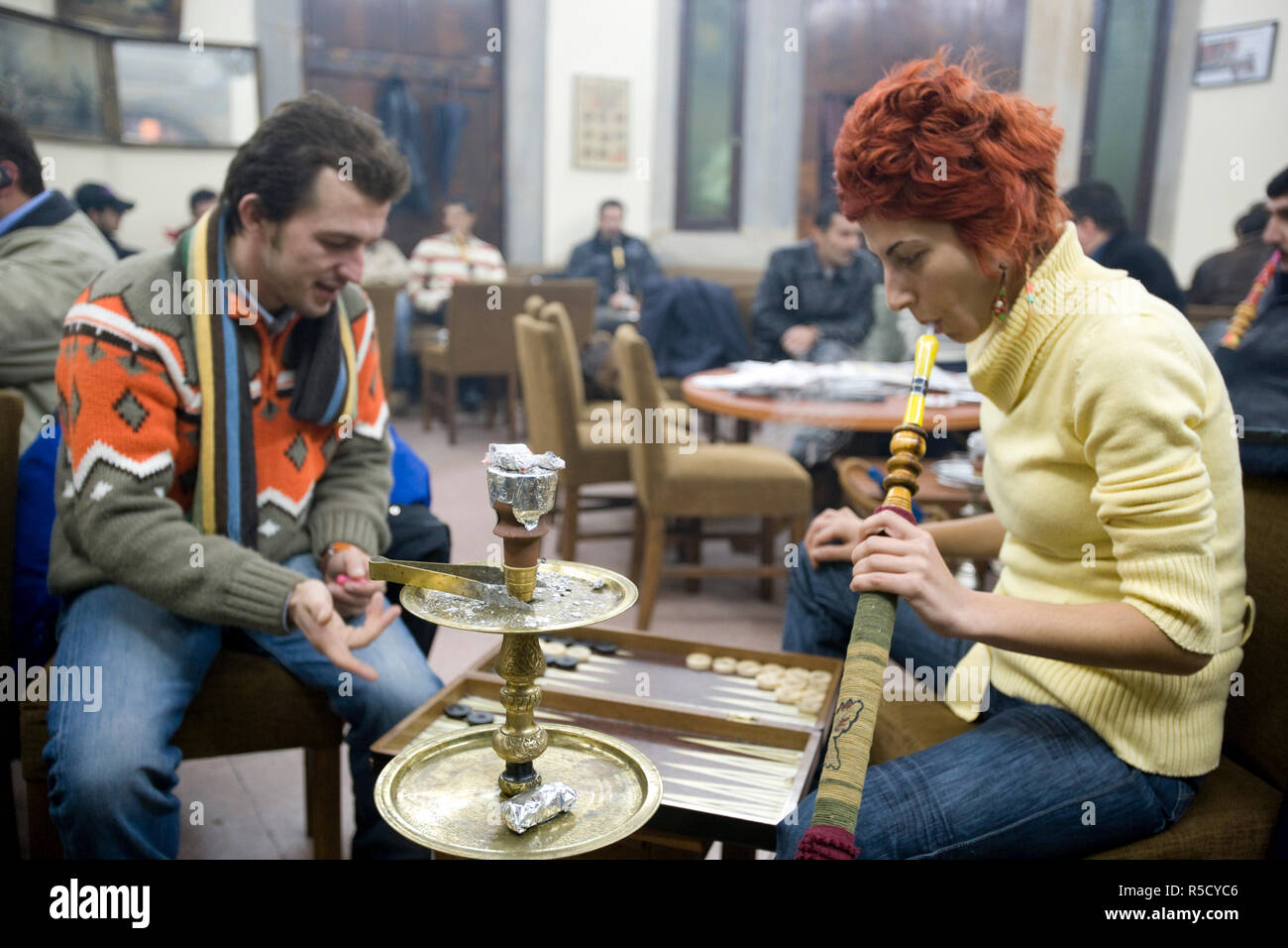 Young Turkish couple playing Backgammon and smoking Nargiles Bubble Pipes inside Corlulu Ali Pasha traditional cafe, Istanbul, Turkey. (MR and PR) Stock Photo