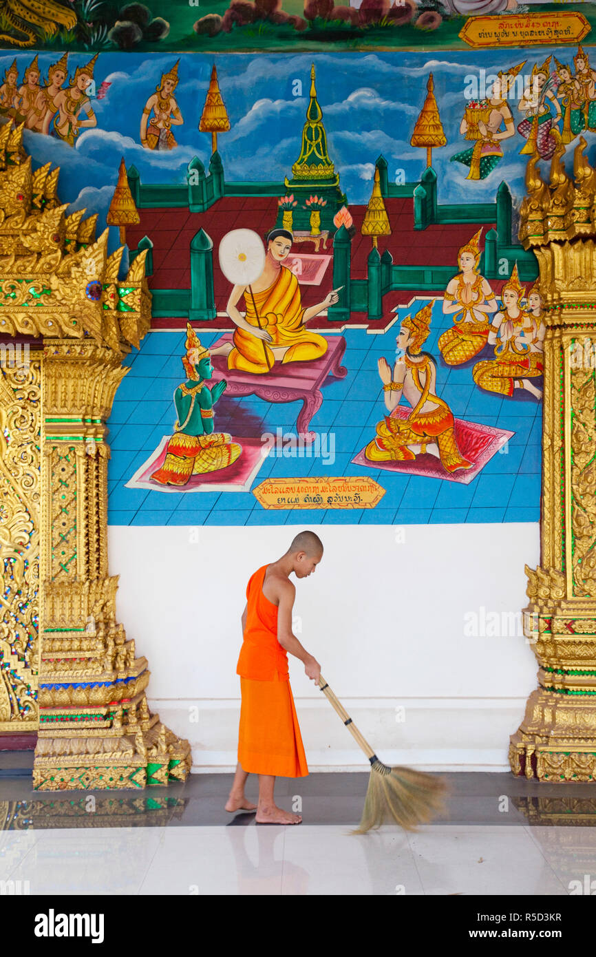Laos, Vientiane, Wat Inpeng, Monk Cleaning Floor of the Main Worshipping Hall Stock Photo