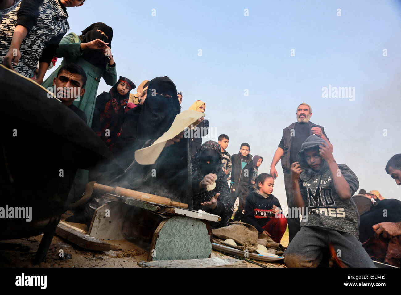 Gaza, Palestinian Territories - 30th November, 2018. A Palestinians women bake bread on firewood traditional, in the 'Great Return Camp' near the border between Israel and Gaza, east of Rafah town in the southern Gaza Strip, on November 30, 2018. Credit: Abdel Rahim Khatib / Awakening / Alamy Live News Stock Photo