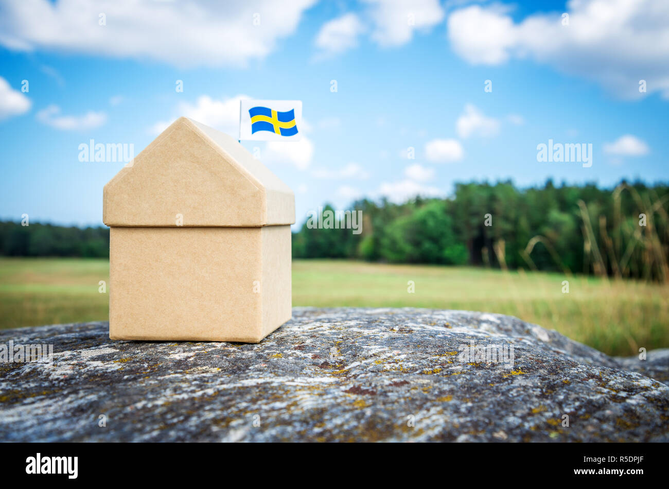 Little cardboard house with a Swedish flag. Scandinavian summer landscape. Stock Photo