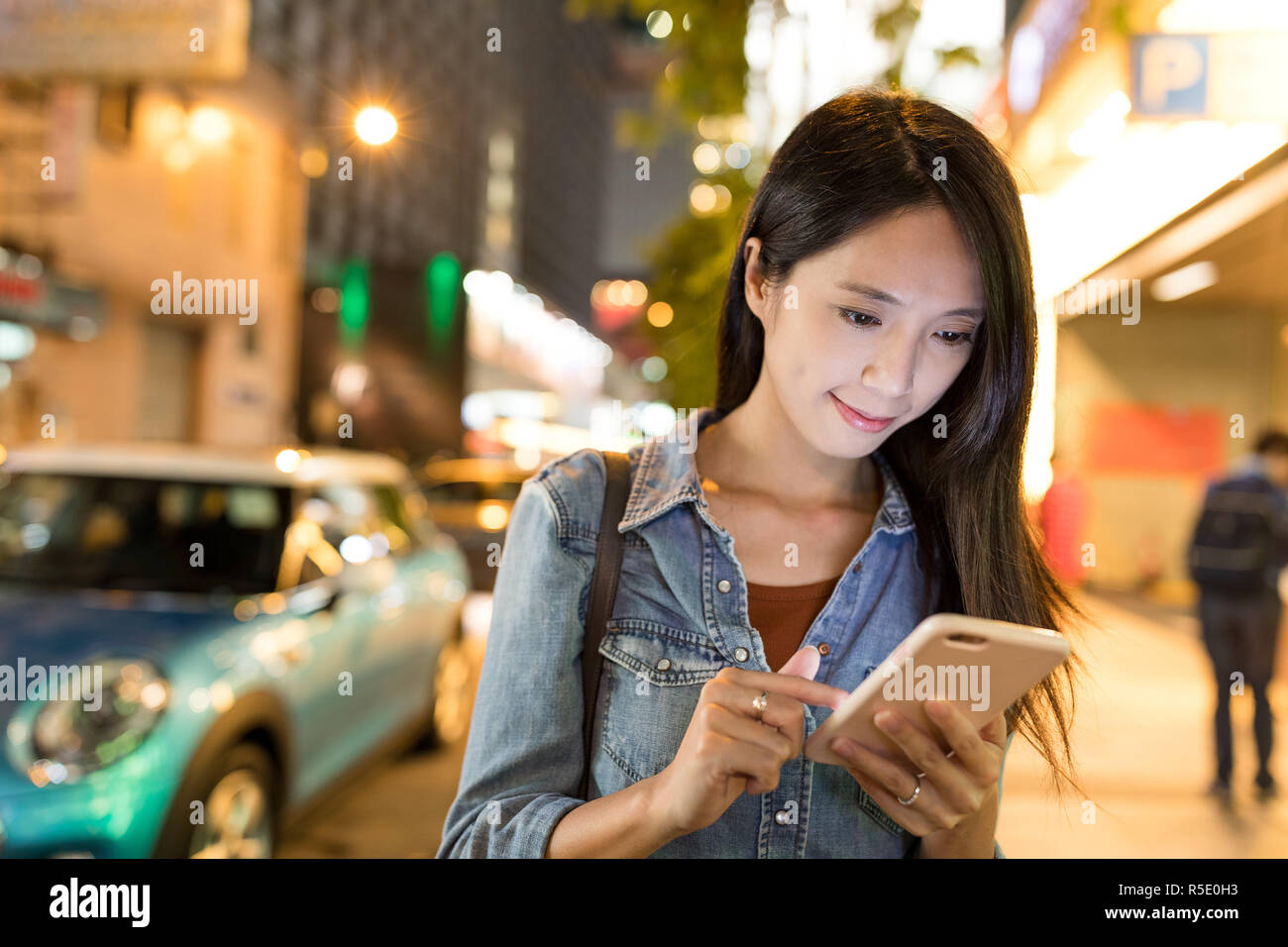 Woman looking at mobile phone in Hong Kong street Stock Photo - Alamy