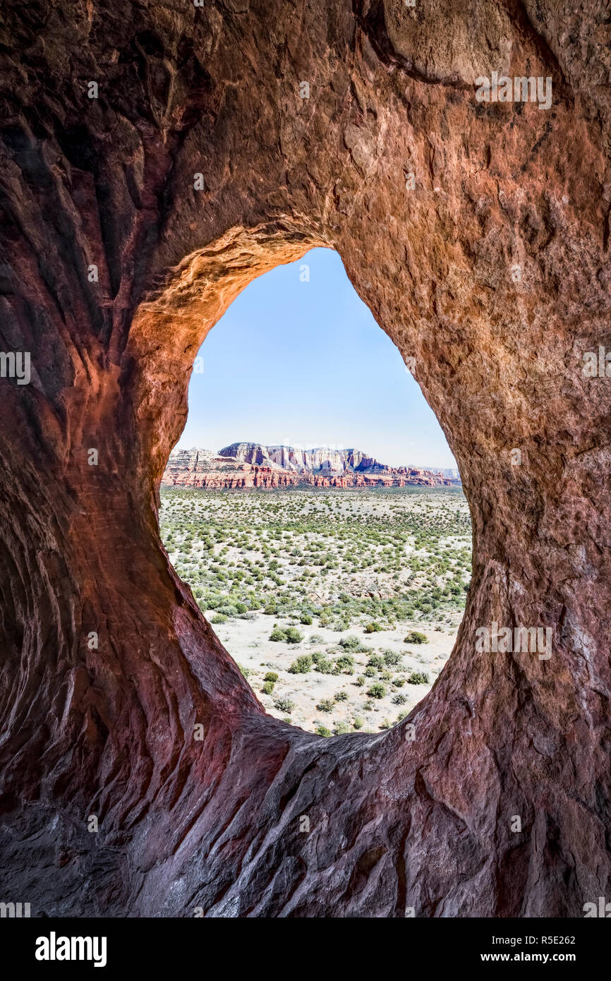 Mesas across a desert valley are viewed from within Robbers Roost, also know as Shaman's Cave and Hideout Cave, not far from Sedona, Arizona. Stock Photo