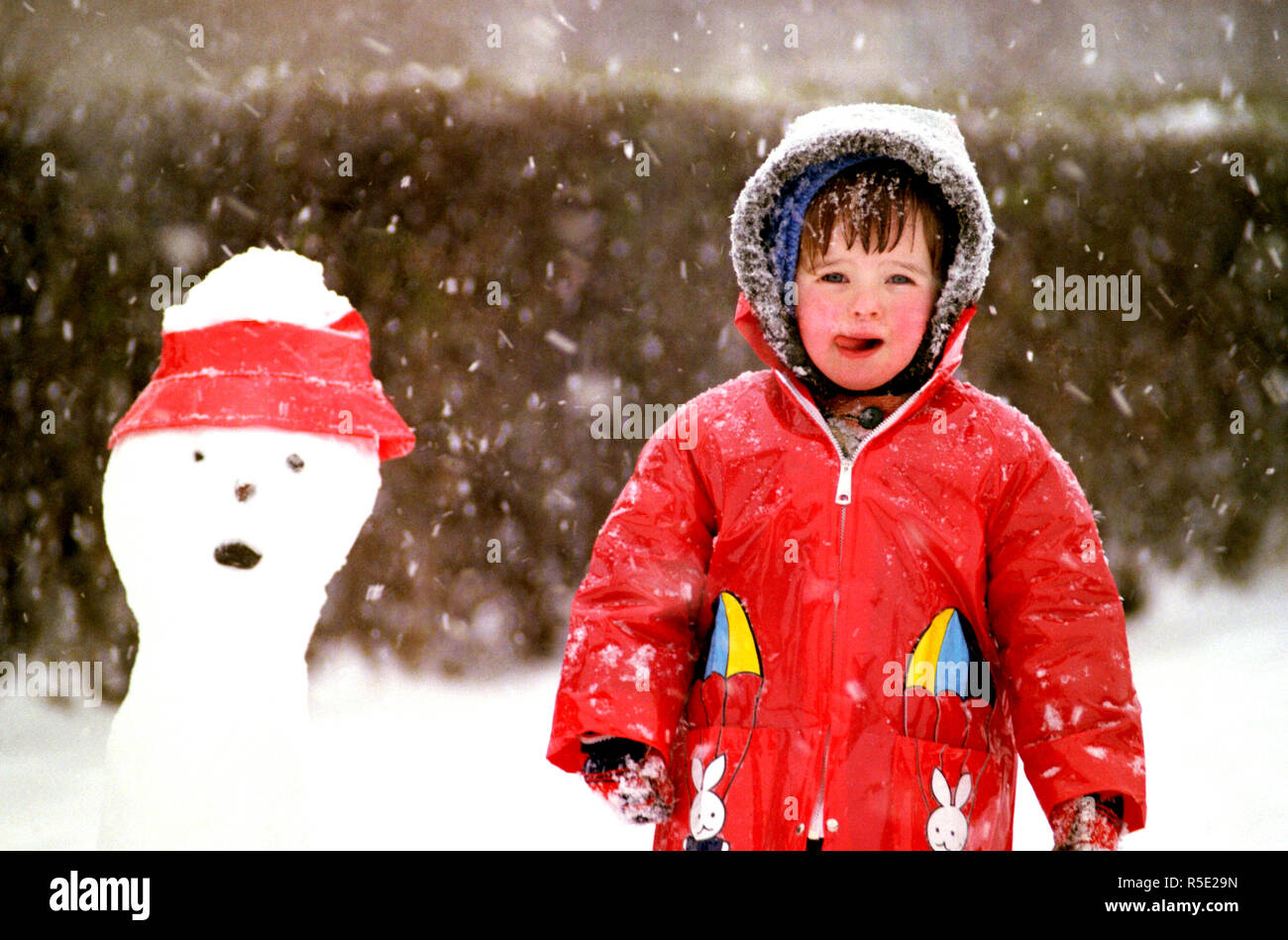 Girl in a red raincoat in the snow. She insisted on going out in a