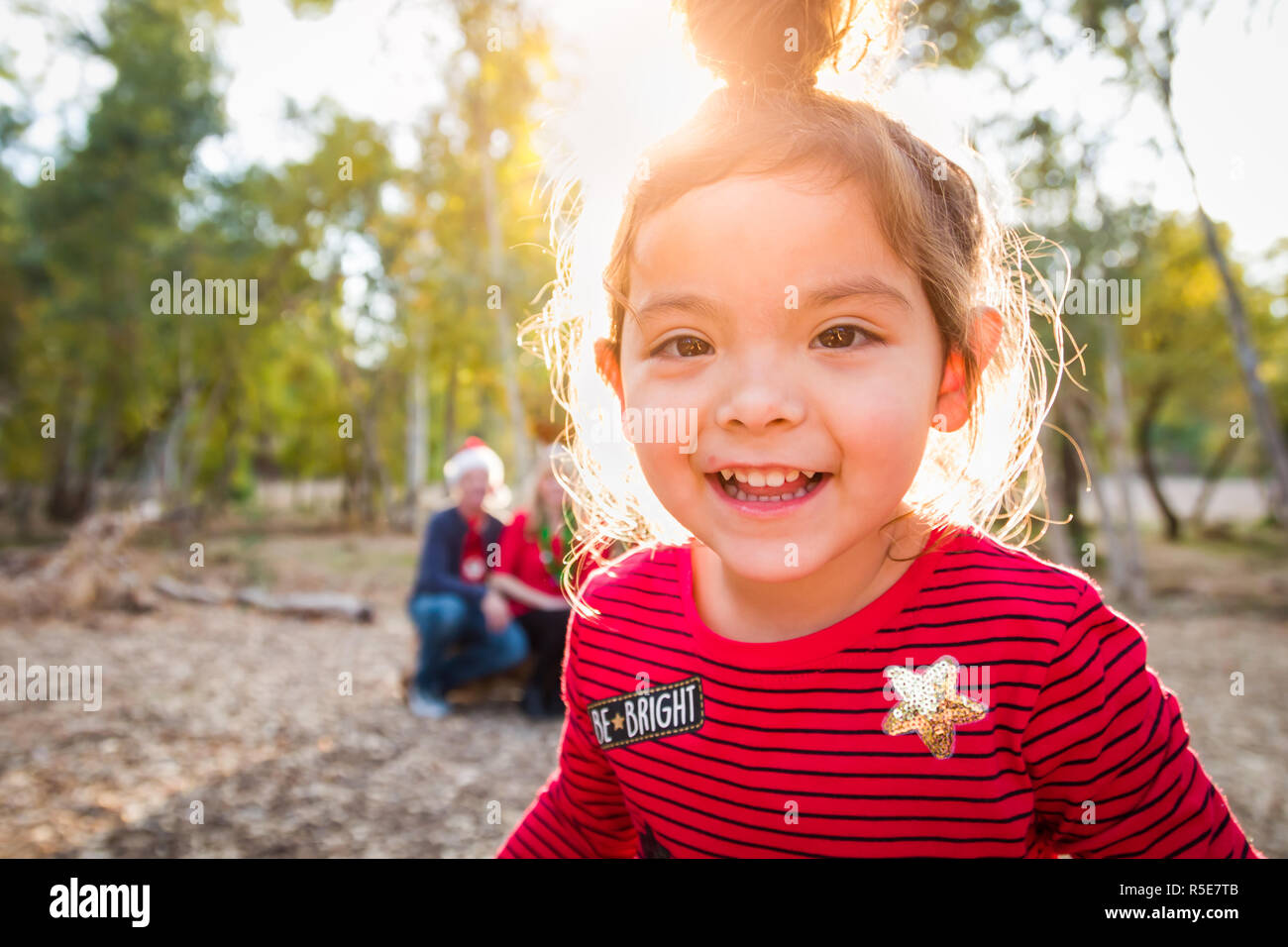 Cute Mixed Race Baby Girl Christmas Portrait With Family Behind Outdoors. Stock Photo