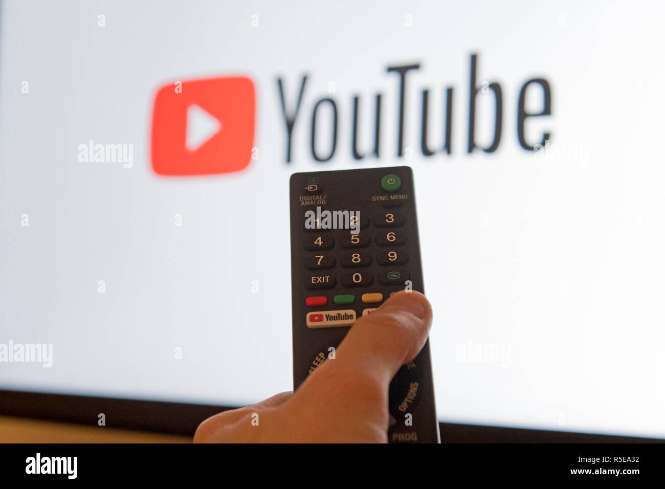 A man points a remote control at a smart television displaying the YouTube app in a bedroom at home in the UK. November 2018. Stock Photo