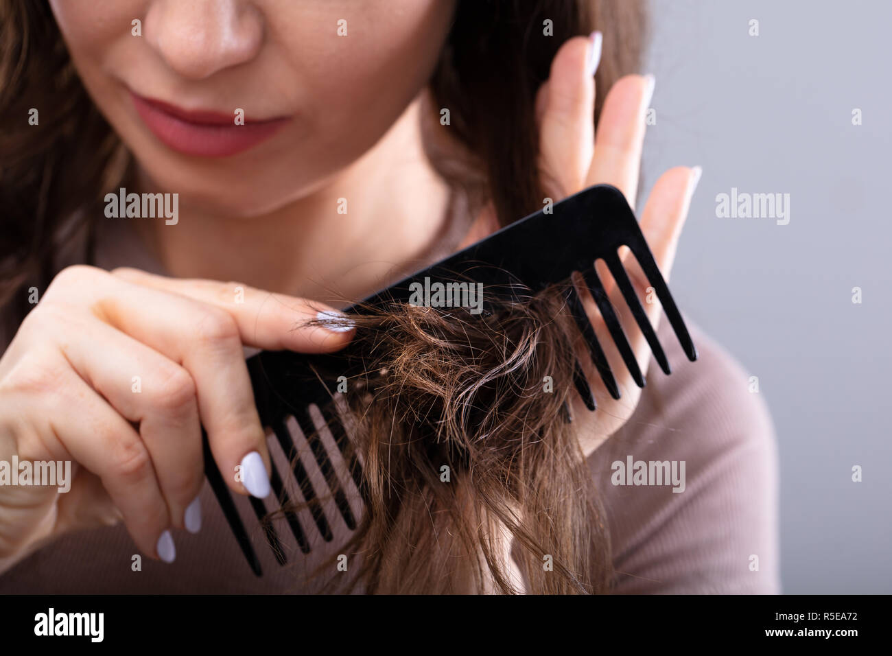 Close-up Of A Woman's Hand Combing Her Hair With Comb Stock Photo