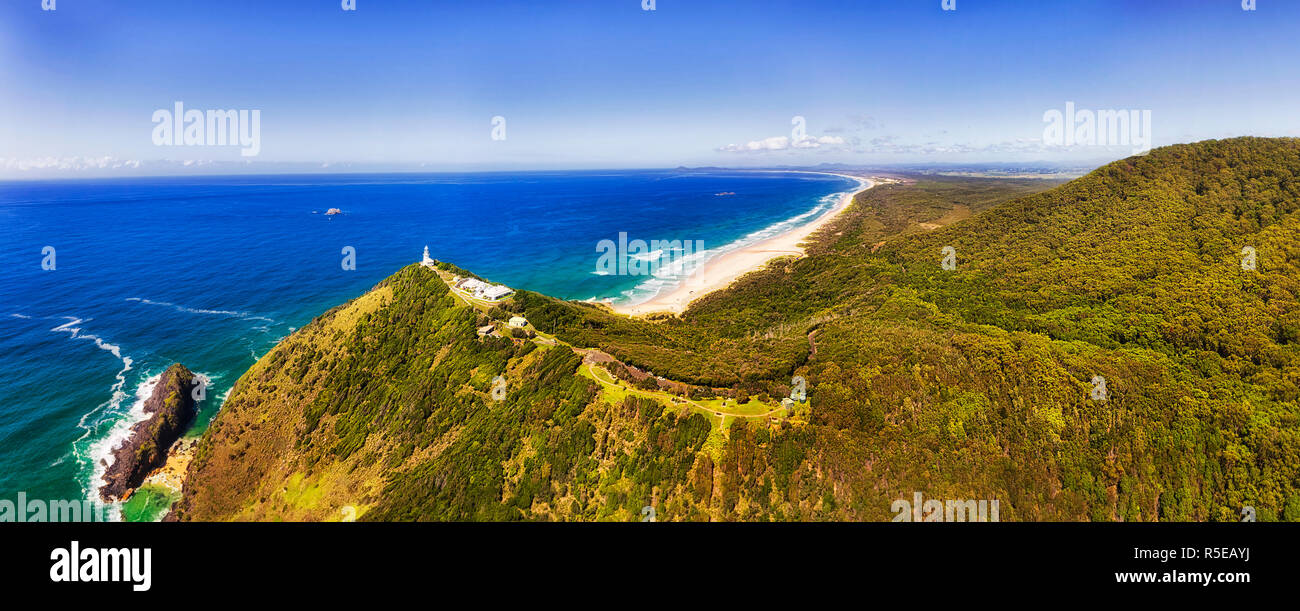 Hill tops of Smoky Cape with elevated while lighthouse facing vistas of Pacific ocean on NSW North coast in Australia. MId-air panorama over lush wood Stock Photo