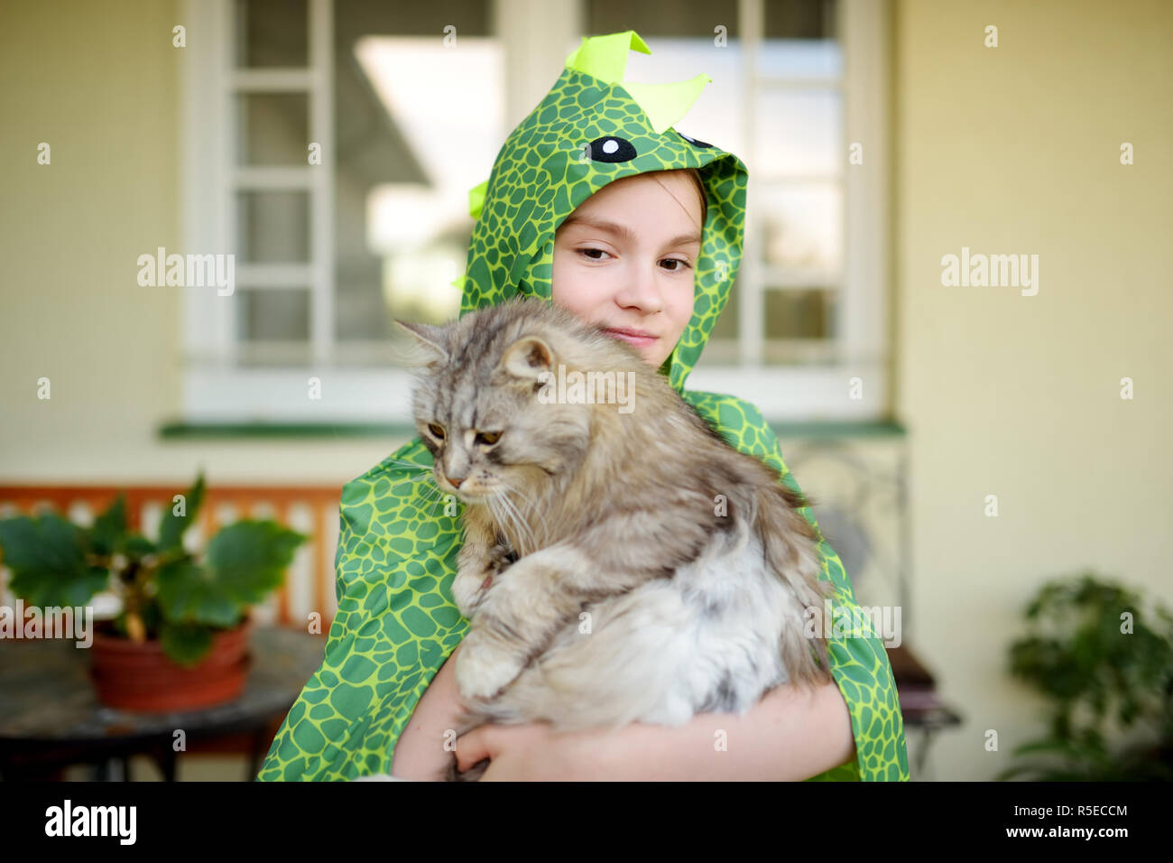 Cute girl wearing fancy costume holding her cat on sunny summer day ...