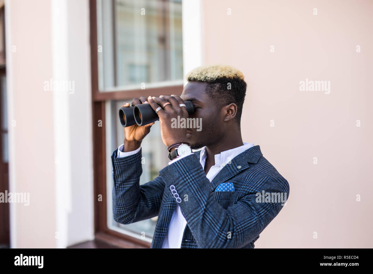 african american electrical manager using binoculars looking at substation Stock Photo