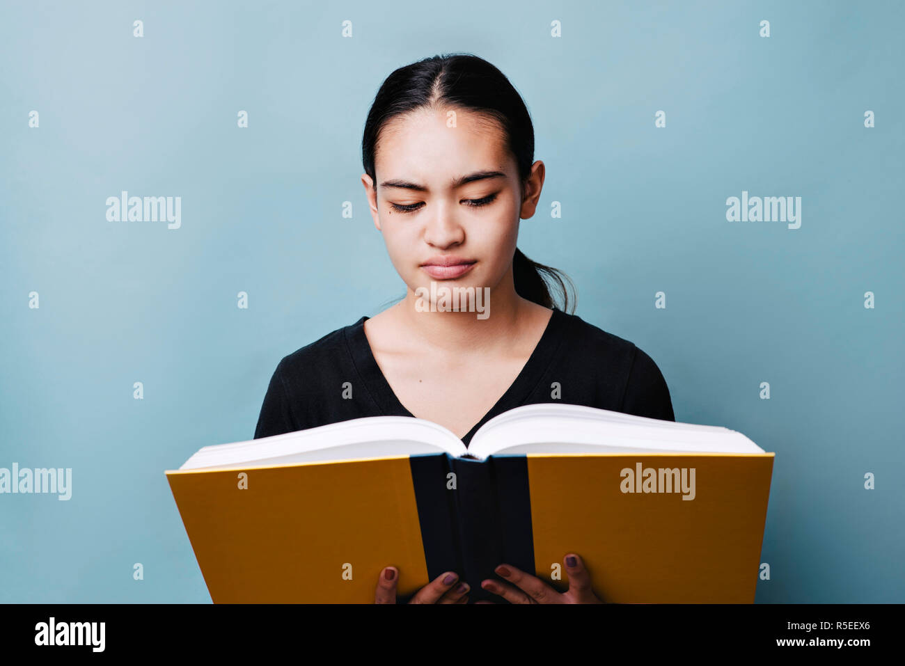 Young teen girl has difficulty reading and understanding content in text book Stock Photo