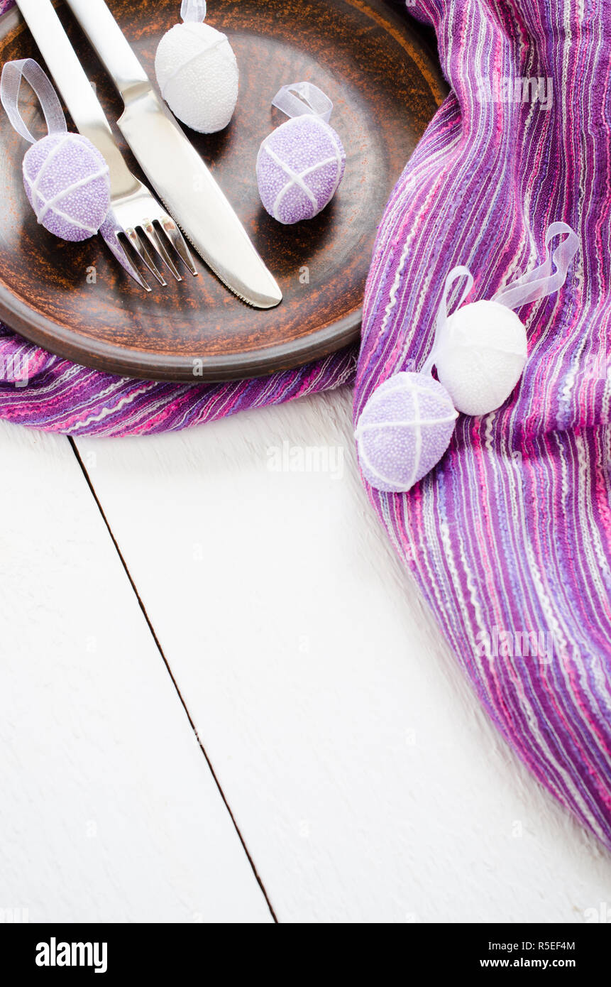 Festive table setting for Easter dinner with easter eggs. Napkin, plate and cutlery on wooden table. Holidays background. Selective Focus. Stock Photo