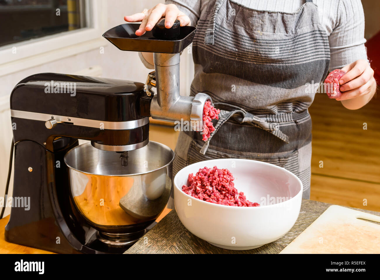 Person using domestic meat grinder while mincing meat at home. Stock Photo